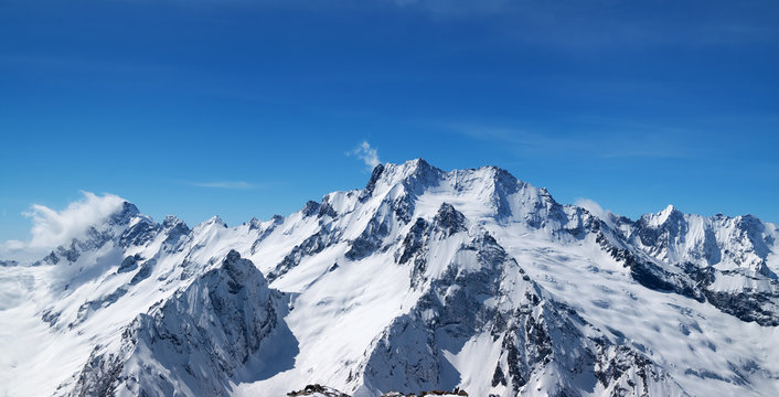 Fototapeta Panoramiczny widok na ośnieżone szczyty górskie i piękne błękitne niebo