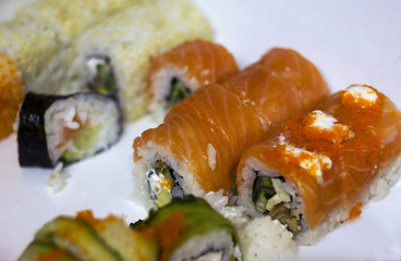Mixed sushi on a white plate, homemade rolls, and Japanese food