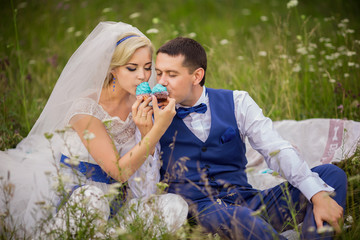 Wedding couple having fun with blue cupcake. Happy bride and groom. Marriage concept