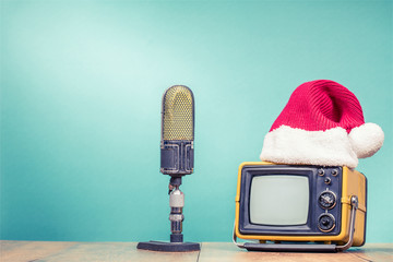 Retro TV in Santa hat and big studio microphone front mint green background. Holidays...