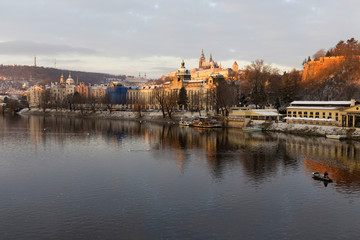 Fototapeta na wymiar Early Morning Christmas snowy Prague Lesser Town with gothic Castle above River Vltava, Czech republic