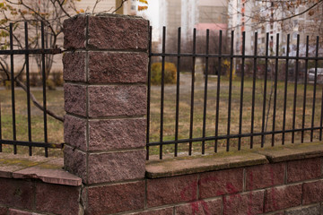 Metal fence with rock columns near multi-storey building