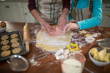 Mother and daughter preparing cookies in kitchen