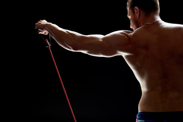 Athletic man using resistance band. Strength training concept. Building perfect dream body.