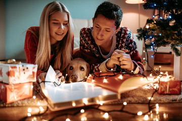 Christmas gifts and happiness between a young couple and a cute dog