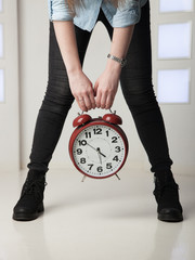 girl with big clock in hands on the background of legs