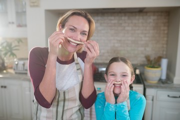 Happy mother and daughter having fun in kitchen