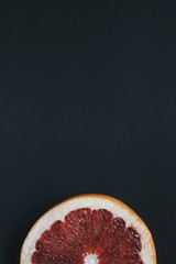 A half of one grapefruit on dark background. Single slice of pomelo.