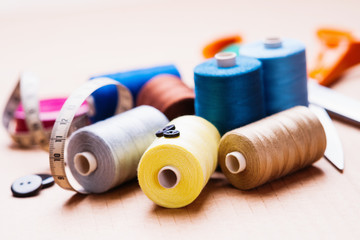 Pile of colorful spools of thread, buttons and measuring meter 