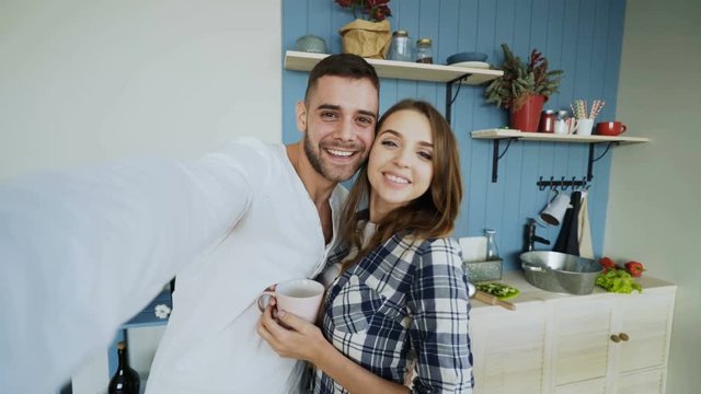 POV of Young happy couple taking selfie photos while having breakfast time in the kitchen at home