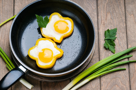 Bell pepper egg rings on a cooking pan, parsley and green onion