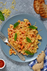 Farfalle with tomato sauce, shrimps and cheese on a concrete background.