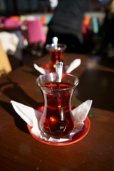 Two tea glasses on table with tea spoons inside the glasses