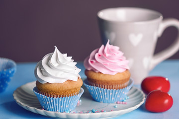 Plate with delicious cupcakes on table