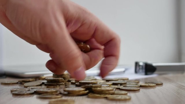 Man hand holding coin dollar on money coin stack arranged as a graph on wooden table. Hand of male or female finger step coins stack growing growth saving money. Business idea.