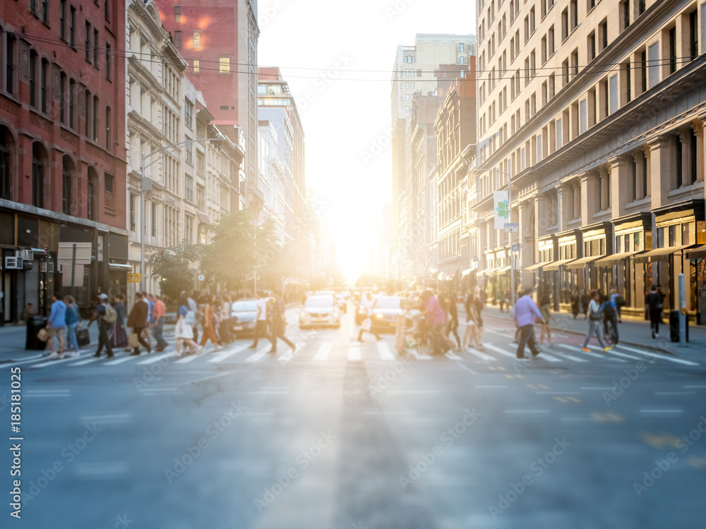 Poster Crowd of anonymous people crossing the street at a busy intersection in Manhattan, New York City with the bright glow of sunset in the background