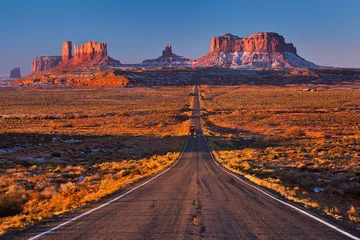Tuinposter A road leading to Monument Valley with red truck going at camera, Usa © Valeriy