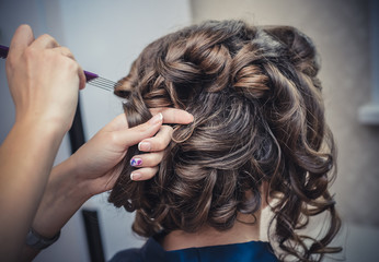 The hands of the hairdresser do wedding hairstyle