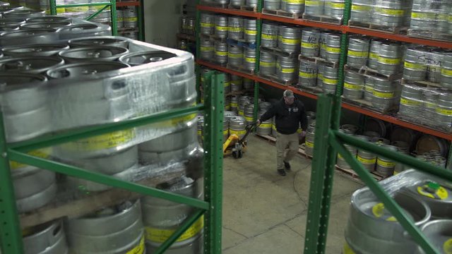 Man pulling a pallet jack full of beer kegs