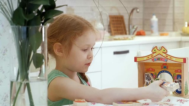 Beautiful girl at the table playing in a puppet theater with toys