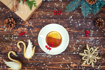 A wooden background with Christmas decorations. A cup of hot tea with lemon.Xmas festive card.New Year , holidays concept.