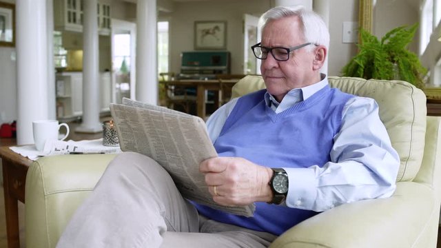 Senior man reading a newspaper at home