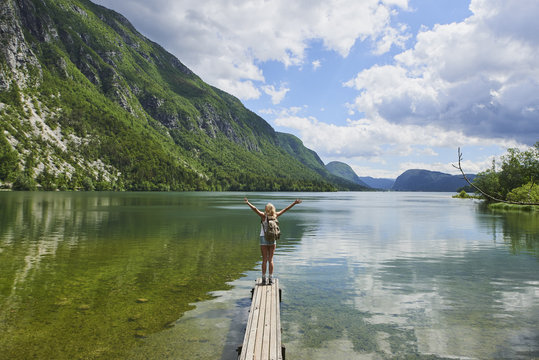 Travel adventure hiker woman celebrates arms outstreched on lake