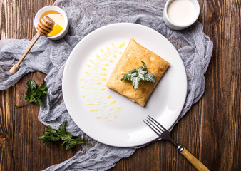 Pancakes with cottage cheese and honey on a white plate on a dark wooden background top view