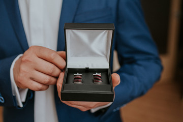 Bestman in blue suit holding box with cufflinks for the grom.