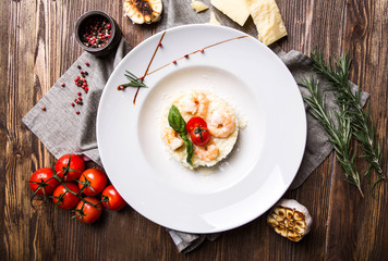Risotto with shrimps in a white plate on a dark wooden background top view