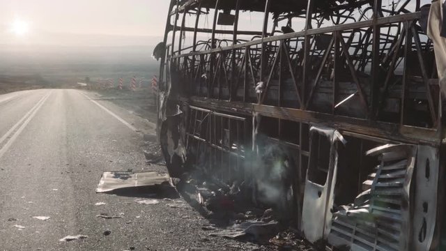 Detail of burnt auto-bus near the road at sunset.