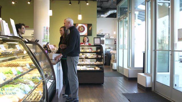 Employee serving mature couple in a bakery