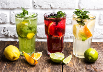 three different cocktails on a white brick wall background