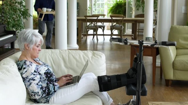 Senior man bringing meal to senior woman sparing her leg on a knee scooter