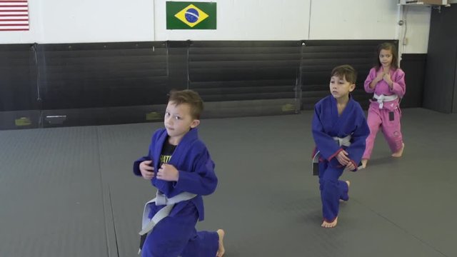 Children doing lunges in a dojo