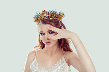 Crowned beauty queen. Blonde curly hair woman fashion model girl purple makeup eye shadow crystals crown looking at camera showing beige nails manicure color in set with lipstick isolated light green
