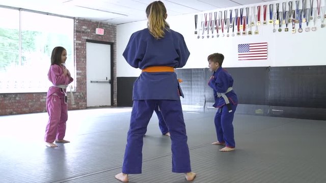Teenage girl practicing Jiu-jitsu with children