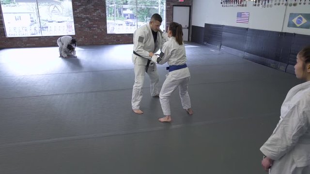 Mid adult man and young woman practicing Jiu-jitsu