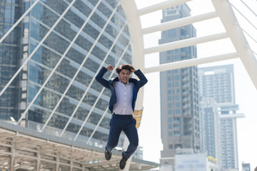 Successful businessman in suit.  He is glad and jumping background in big city. Business concept, Lifestyle concept..