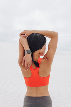 Woman stretching her arms wearing a sports bra and watch
