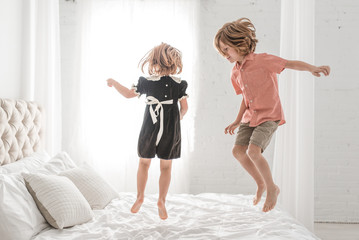 Siblings Jumping Together On A Bed
