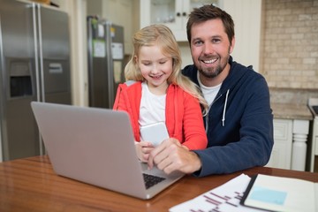 Father and daughter working on laptop