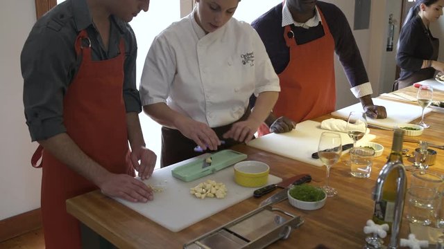 Chef showing a student how to grate garlic