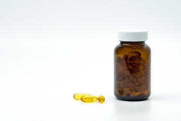 Yellow fish oil capsule pills with amber glass bottle with blank label on the table with copy space for text. Vitamins and supplements for heart care and joint care. Source of omega 3, EPA and DHA.