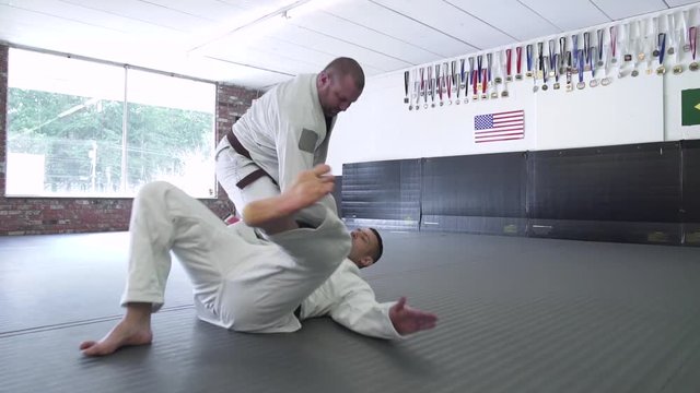 Mid adult men practicing Jiu-jitsu in a dojo