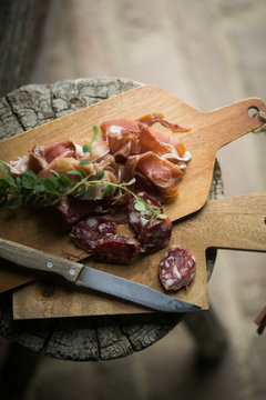 Cut salami and ham laying on wooden table