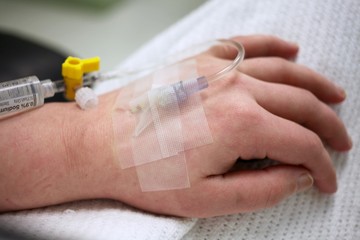 Close up of an IV needle in a patients hand at the hospital