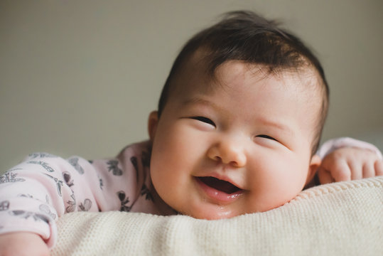 Close-up of a smiling baby girl lying on bed