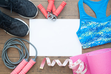 Flat lay of Fitness equipments. Healthy and Diet concept. Yoga mat, sneakers, sport bra, measuring-tape, water on wooden background with copy space