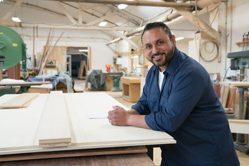 Side portrait of smiling hispanic cabinet shop worker